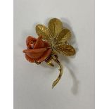 An 18ct gold brooch with coral rose, some chips, measures 6cm with a combined weight of 14.2