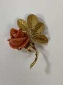 An 18ct gold brooch with coral rose, some chips, measures 6cm with a combined weight of 14.2