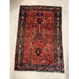 A Hand knotted Persian rug, the red field with stylised foliate enclosed by a triple guarded border,