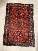 A Hand knotted Persian rug, the red field with stylised foliate enclosed by a triple guarded border,