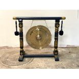 A large brass floor standing dinner gong, on a blue and gilt painted carved trestle frame, with