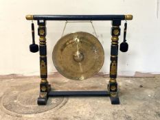 A large brass floor standing dinner gong, on a blue and gilt painted carved trestle frame, with