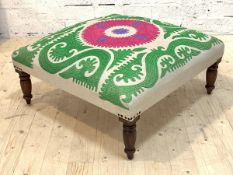 A large upholstered footstool, the top covered in natural linen worked in a vibrant embroidered