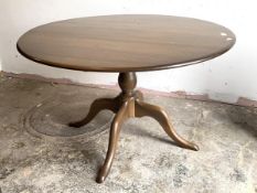 Ercol, A stained elm and beech dining table, the circular top raised on a turned column and four