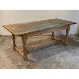 A pine farmhouse style dining table, the rectangular top on turned and block supports united by a