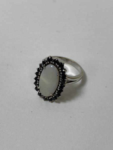 A ladies' dress ring with oval opal surrounded by sapphires in a white metal setting, size M