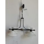 A twin ceiling pendent light fitting, the patinated scrolled metal frame supporting two domed