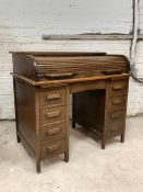 An early 20th century oak roll top desk, the tambour top revealing fitted interior, over two