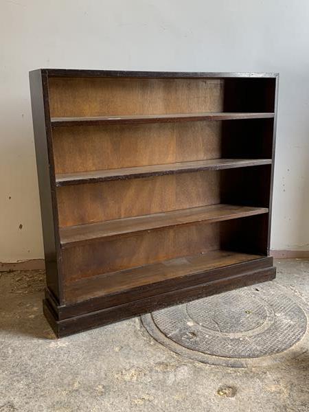 A 20th century stained pine three tier open bookcase on a plinth base, H99cm, W110cm, D23cm