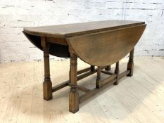 A George III style oak wake dining table, the oval top with twin drop leaf on ring turned and