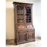 An early 20th century oak bureau bookcase, the dentil cornice over twin glazed doors enclosing three