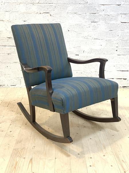 A stained walnut framed open arm rocking chair, the back and over stuffed seat upholstered in blue