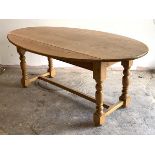 A pine wake style dining table, the oval top with two drop leaves over turned and block supports