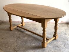 A pine wake style dining table, the oval top with two drop leaves over turned and block supports