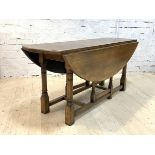 A George III style oak dining table, oval top with twin drop leaf on ring turned and block gate