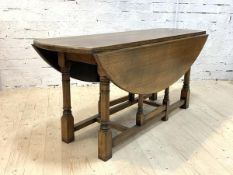 A George III style oak dining table, oval top with twin drop leaf on ring turned and block gate