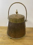 An early 20thc brass and copper coal scuttle of conical form with swing handle, floral and crest