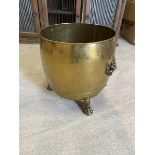 A brass log bin, lion mask ring handle to sides, raised on three paw feet, measures 41cm x 39cm