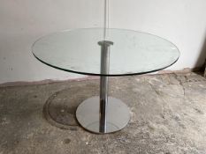 A modern glass circular dining table on chrome support and circular base, measures 75cm x 110cm