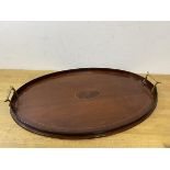 An early 20thc mahogany oval thin brass handled drinks tray, measures 38cm x 56cm