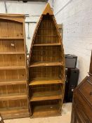 A modern floor standing pine bookshelf in the form of an upright row boat with four shelves,