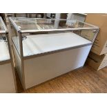 A modern display jewellery counter with glass to top and sides, sliding glass opening to back,