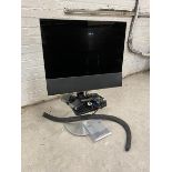 A Bang & Olufsen television with sensory swing action ability, on stand, measures 24", along with