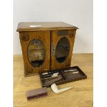 An early 20thc table top smokers cabinet with arrangement of drawers and compartments to interior,