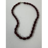 A graduated string of oval amber beads