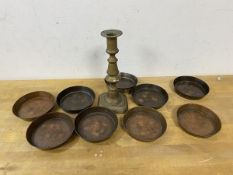 A collection of copper dishes, each measuring 9cm diameter (9) and a brass candlestick (a lot)