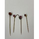 A set of three yellow metal stick pins with amethyst finial's with orange coloured stone, measures