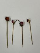 A set of three yellow metal stick pins with amethyst finial's with orange coloured stone, measures