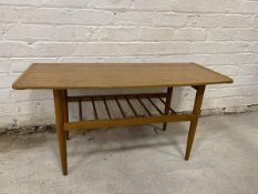 A Mid Century style coffee table with walnut veneered top, upturned short ends on turned tapering