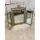 A distressed Georgian style triple swing mirror with ribbon crest over hinged central mirror flanked