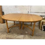 A blonde extending Ercol dining table, the oval top with two additional leaves, raised on turned and