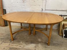 A blonde extending Ercol dining table, the oval top with two additional leaves, raised on turned and