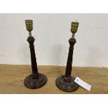 A pair of brass column style candlesticks, on carved wooden bases, measure 26cm high