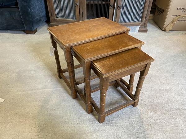 A 1930's 40's oak set of three nesting tables on turned supports, largest measures 46cm x 34cm x