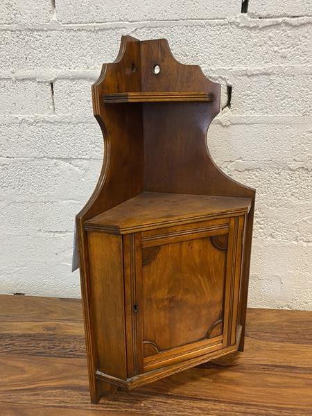 An Edwardian walnut tabletop corner cabinet, the moulded edge united by upper shelf over cabinet