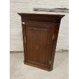 A George III oak hanging corner cabinet, the projecting cornice over an inlaid mahogany frieze,