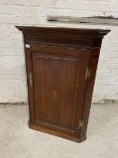 A George III oak hanging corner cabinet, the projecting cornice over an inlaid mahogany frieze,