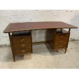 A Mid Century teak desk, the concave top with tooled leather writing surface with recess to either