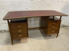 A Mid Century teak desk, the concave top with tooled leather writing surface with recess to either