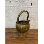 An early 20thc helmet style brass coal scuttle with adjustable handle, measures 43cm high with