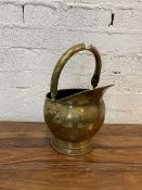 An early 20thc helmet style brass coal scuttle with adjustable handle, measures 43cm high with