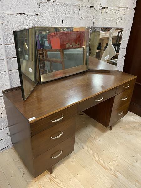 A Mid Century teak veneerered dressing table with triple swing mirror over one long and six short