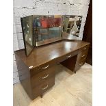 A Mid Century teak veneerered dressing table with triple swing mirror over one long and six short