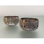 A matched pair of small Thai silver bowls, unmarked, each chased with figural cartouches above a