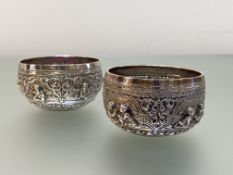 A matched pair of small Thai silver bowls, unmarked, each chased with figural cartouches above a