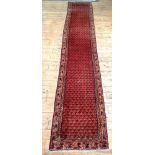 A hand knotted Persian Seraband design runner rug, the red field with boteh motif and bordered 400cm